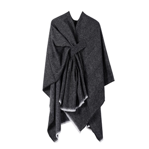 Close-up of dark grey knitted shawl with slanted hem and fringe tassel details
