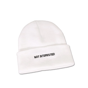 Detailed close-up of 'NOT INTERESTED' embroidery on a white folded knit beanie