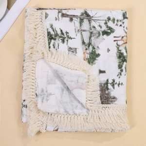 Detail of baby muslin blanket with forest animal print and decorative tassel edge