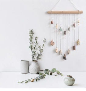 Detail of natural crystal stones hanging from wooden stick wall decor with metal chains