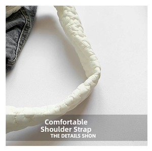 Detail of white quilted wide shoulder strap and denim patchwork on a stylish underarm bag