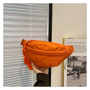Detail of orange nylon chest bag with woven rope puller and double zipper pockets