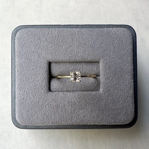 Top view of a gold square moissanite ring resting in a premium grey velvet jewelry box