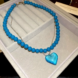 Close-up of vibrant blue beads and translucent heart pendant in a premium velvet gift box