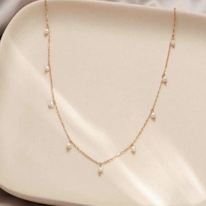 18K gold plated stainless steel necklace with delicate white pearls on ceramic tray