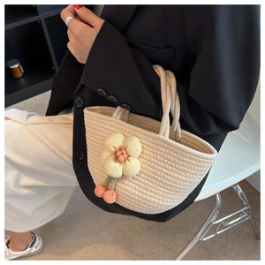 Detail of cream woven cotton handbag with yellow flower charm for minimalist casual style
