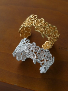 Detailed close-up of 18k gold and silver hollow flower bangle with intricate metal lace patterns