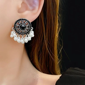 Detail of vintage round stud earrings with black crystals and white pearl tassels
