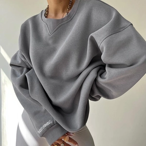 Detail of grey oversized sweatshirt showing V-stitch neckline and INSTUNNING sleeve text