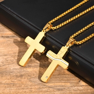 Detailed close-up of two golden stainless steel cross pendants with diamonds on black leather