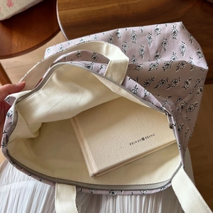 Detailansicht der lila floralen Canvas-Tasche mit weißem Reißverschluss und Tragegurt