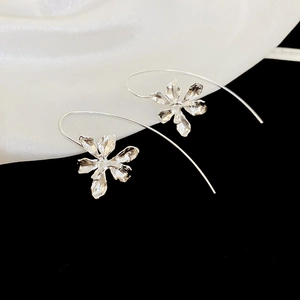 Detailed view of silver iris flower earrings on a luxury black and white silk background