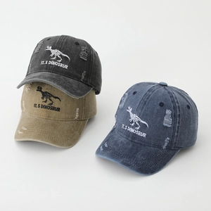 Close-up of distressed baseball caps with dinosaur skeleton embroidery and ripped details
