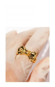 Close-up of gold-plated brass bow ring with polished mirror finish and textured detail