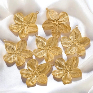 Set of golden stainless steel flower pendants with radial texture on white silk fabric