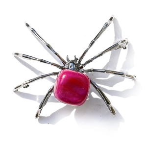 Macro detail of silver spider ornament featuring a large pink square crystal gemstone