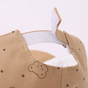 Dettaglio cinturino in velcro ed elastico su berretto kaki per neonati a pois e orso