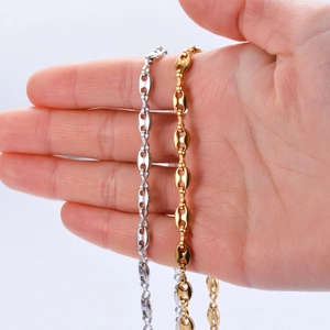 Detail of stainless steel coffee bean chain in gold and silver finish held by hand