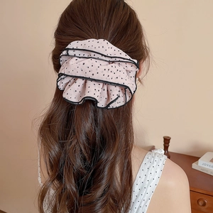 Detailed view of the oversized pink polka dot scrunchie styled on a ponytail