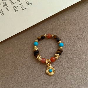 Detail of beaded stretch ring with tiger eye agate and gold-plated wavy charm