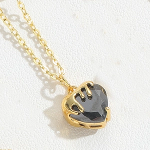 Macro shot of gold heart necklace with black zircon and liquid metal style detail