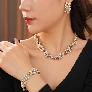 Close-up of vintage gold pearl necklace and earrings set worn by a model