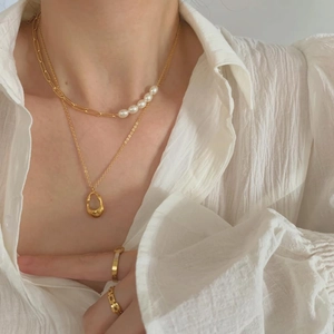 Chic gold layered necklace with pearl chain splicing and drop pendant on a model