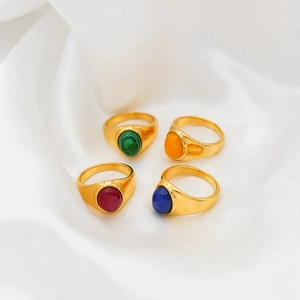 Close-up of four vintage 18k gold plated rings with red, blue, green and orange agate stones
