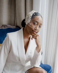 Detail of white bridal veil with faux pearl floral accents and mesh texture on a model