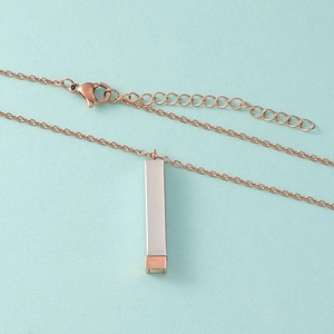 Détail de la chaîne en or rose avec pendentif rectangulaire argenté et fermoir mousqueton