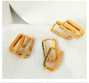 Close-up of geometric gold earrings set with rainbow and green zircon stones