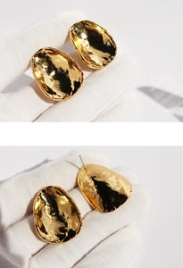 Detailed macro view of gold pebble-shaped earrings with hand-hammered artistic texture