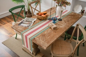 Detail of woven cotton linen table runner with red green patterns and decorative tassels