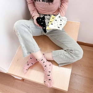 Detailed shot of cotton bow socks in pink, black, and white on a wooden floor
