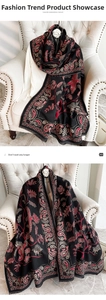 Detail of cashmere scarf showing paisley bird print and fringe on a white sofa