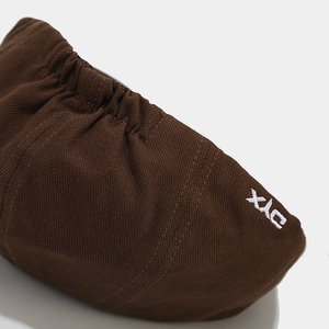 Close-up of coffee brown fabric texture and white XJC embroidery on a retro newsboy cap