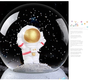 Detail view of astronaut figure inside a crystal ball with snow-like glitter elements