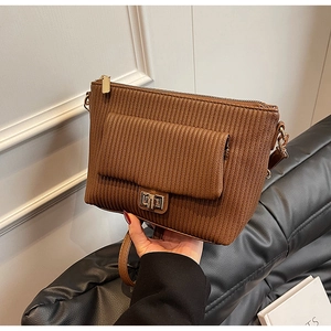 Detailed view of the brown textured leather surface with a gold metal twist-lock and zipper