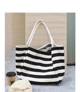 Close-up of a striped canvas tote bag with woven rope handles in an outdoor setting