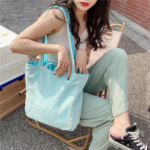 Bolso tote de lona con cuadros azules y blancos en un entorno de camping al aire libre