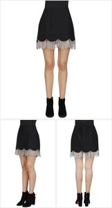 Detail of high-waist black mini skirt with sparkling silver rhinestone tassels and wavy hem