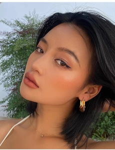 Close-up of model wearing U-shaped gold and amber resin geometric hoop earrings