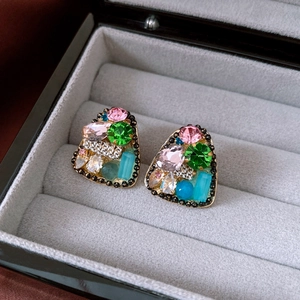 Close-up of vintage gold triangle earrings with colorful crystals on grey velvet