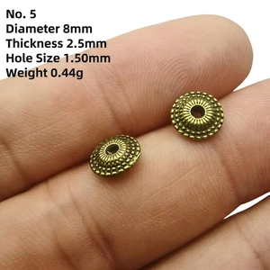Macro detail of 8mm bronze wheel spacer beads on a fingertip for jewelry making