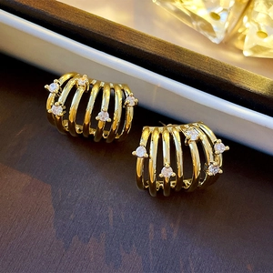 Macro detail of gold-plated multi-layer C-shaped earrings with sparkling cubic zirconia