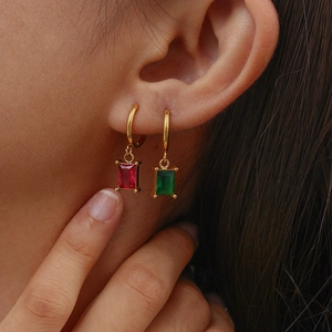 Close-up of gold hoop earrings with emerald and ruby geometric zircon pendants