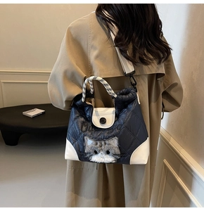 Detail of navy quilted tote with cat plush and white contrast flap on female model