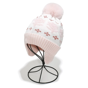 Detailed close-up of knitted winter earflap hat with pink flower jacquard and pom-pom