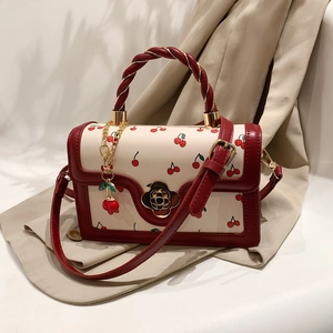 Fashionable cherry print shoulder bag with red rope handle and flower metal clasp