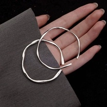 Detailed view of silver heart bracelet with elegant twisted wavy texture on female wrist